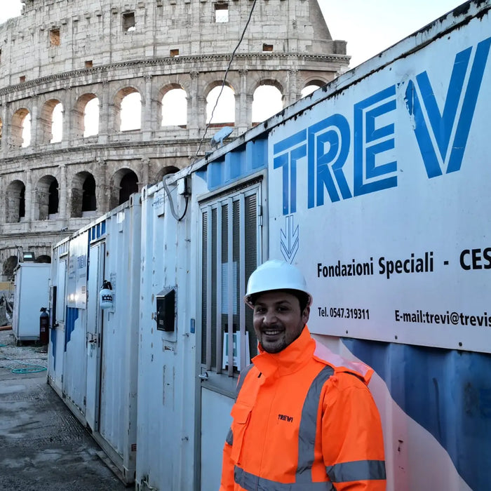 Lavoratore edile con casco e giubbotto arancione vicino al Colosseo, testimonianze ex allievi.